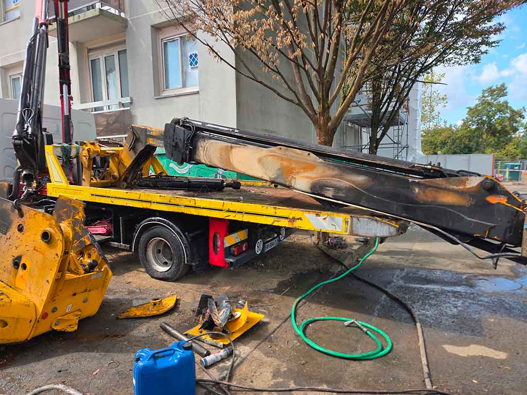 Chariot télescopique JCB incendié chargé sur un camion plateau à bras hydraulique